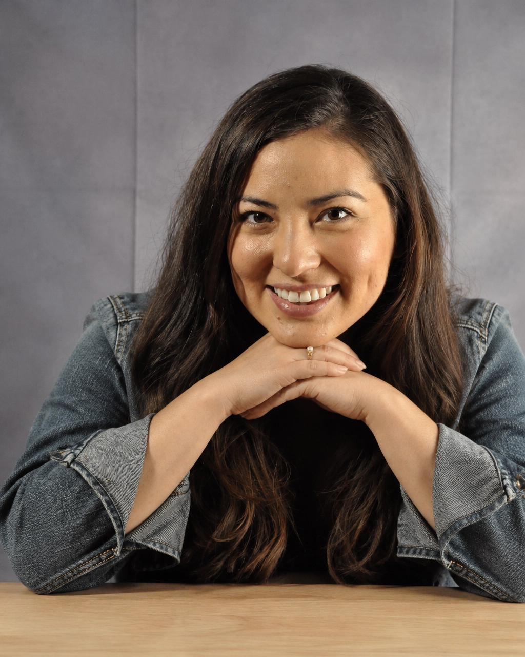 Cassandra Z. Drake smiling with her hands resting on a wooden table